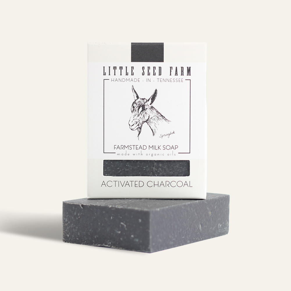 A detoxifying Activated Charcoal Bar from Little Seed Farm sits in front of its packaging, labeled with the brand and a sketch of a goat.