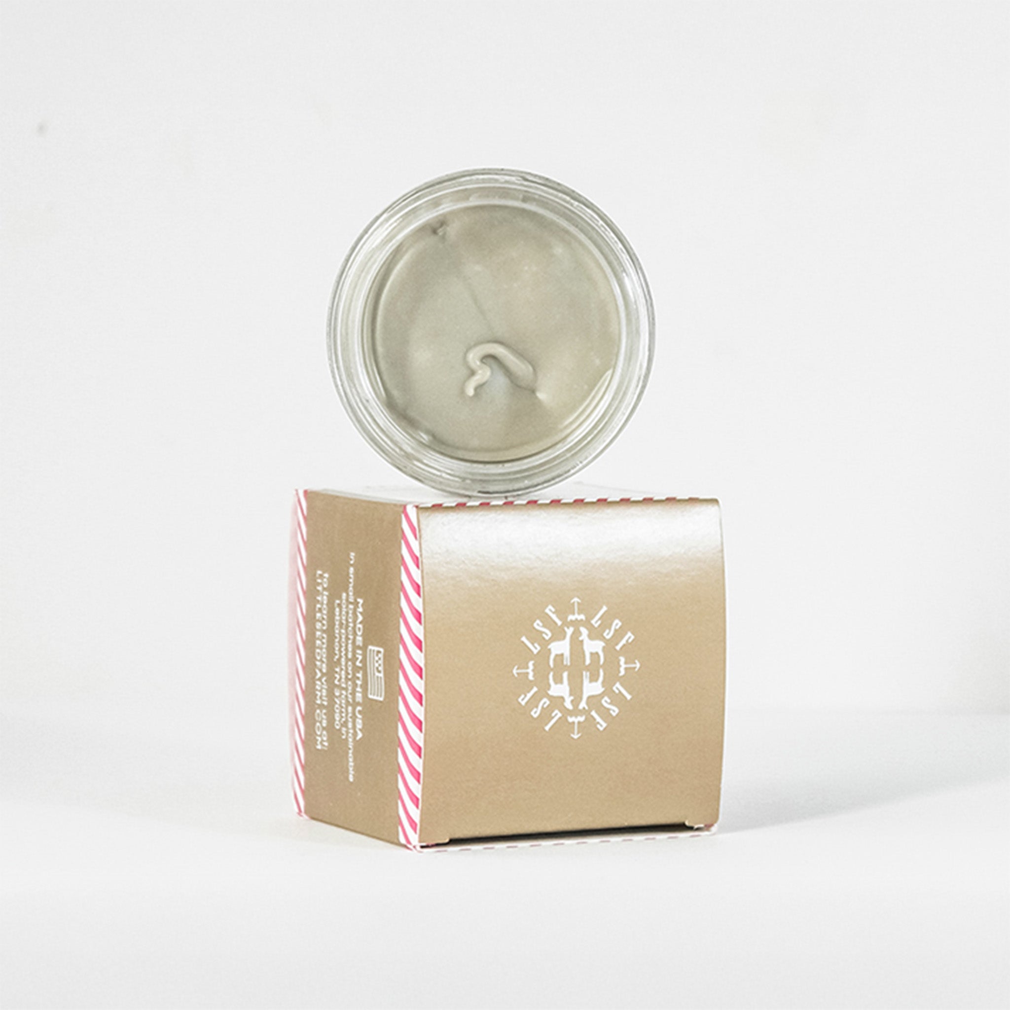 Close-up of Holiday Deodorant Cream texture inside jar, creamy light tone showing activated charcoal blend