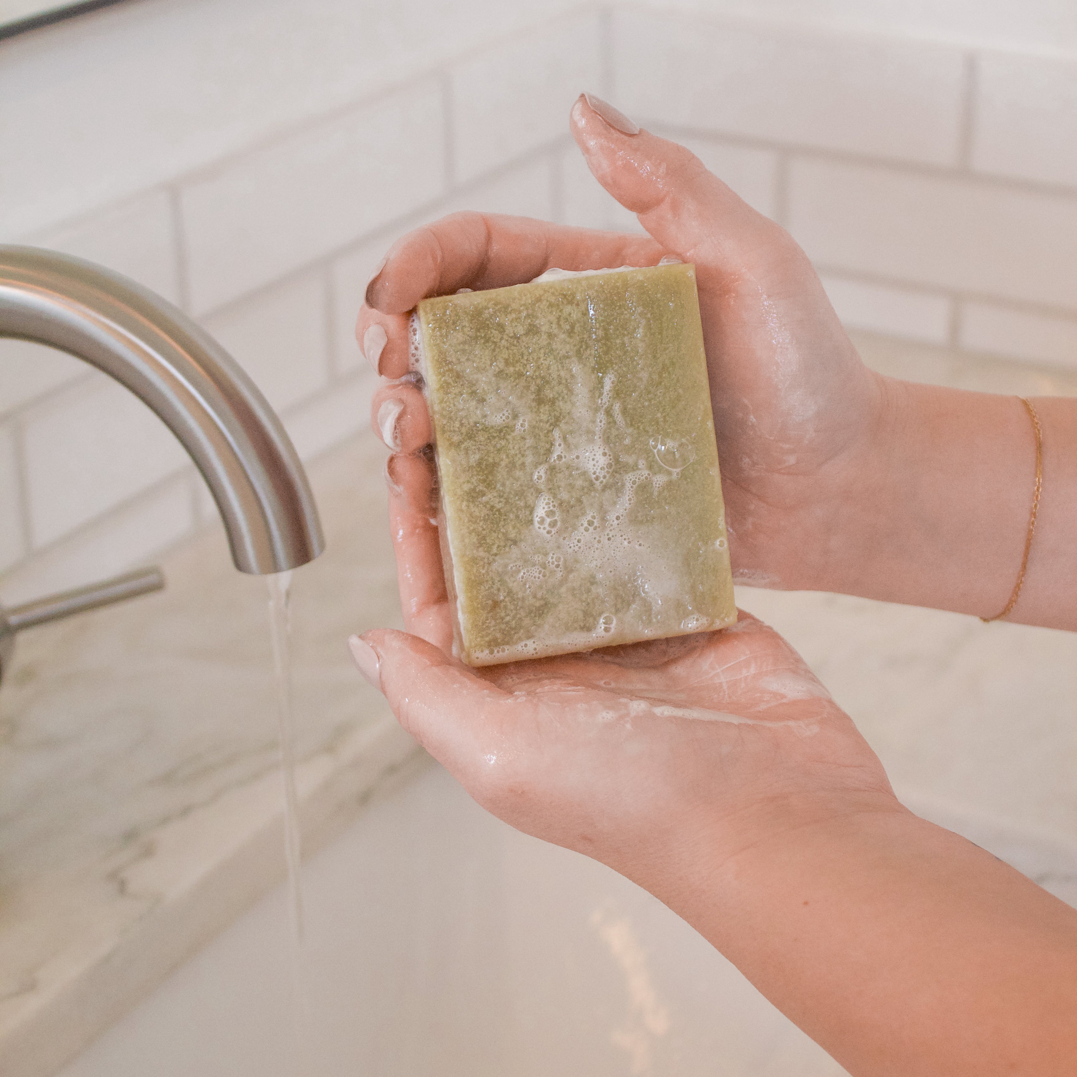 Pair of hands holding a Blue Tansy Rose goat milk soap bar highlighting Little Seed Farm’s natural, soothing skincare made with blue tansy and rose essential oils.