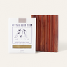 The Little Seed Farm Soap Bar + Dish Set, featuring an oat-scented milk soap and a cedar soap dish with vertical grooves, is displayed against a simple light backdrop.