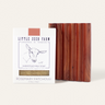 A Little Seed Farm Soap Bar + Dish Set features a Rosemary Patchouli milk soap and a handmade cedar dish. The packaging displays a goat illustration and product details, emphasizing the natural goat milk ingredients inside.