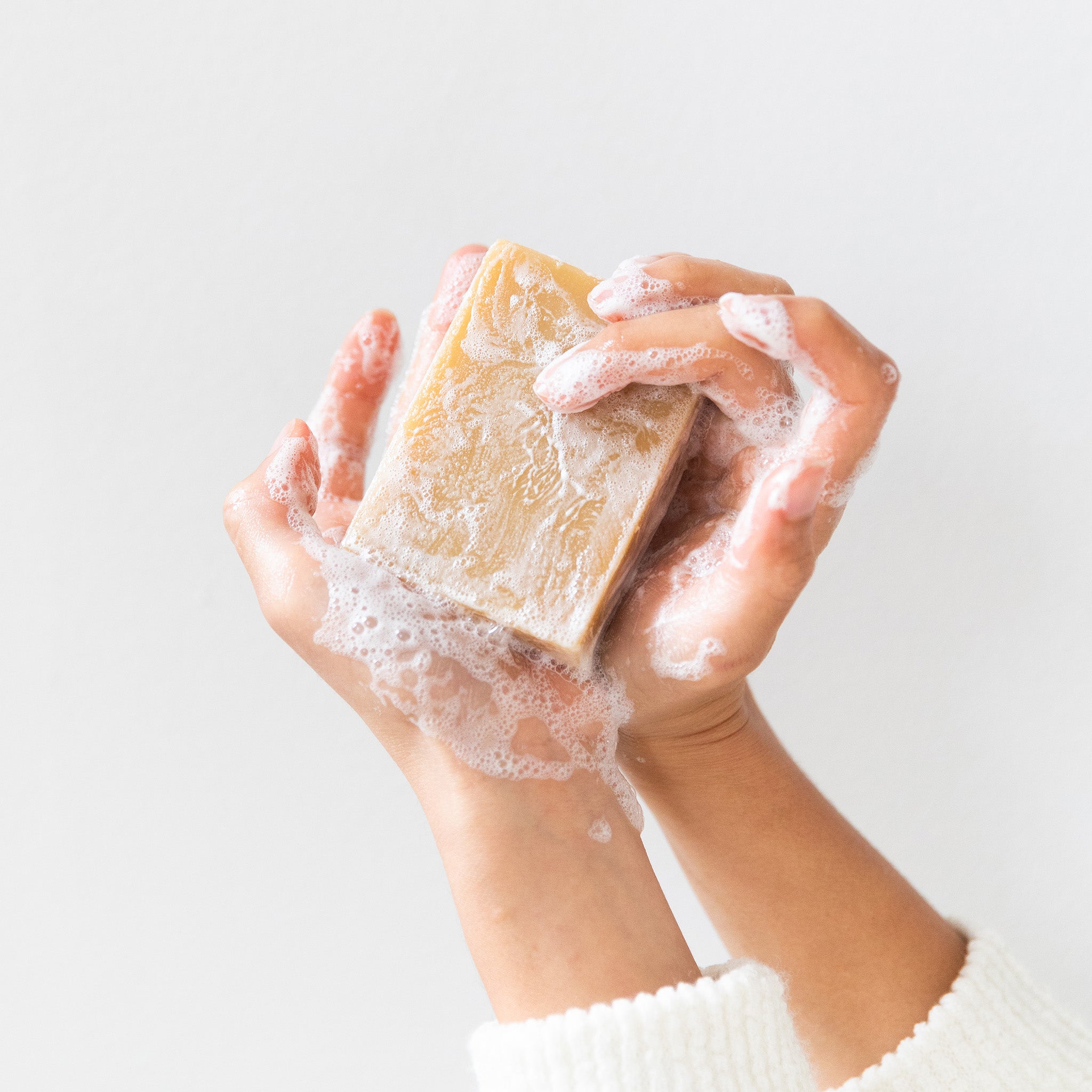 Hands holding a lathered bar of Little Seed Farm goat milk soap, rich in organic oils and natural ingredients for a creamy, skin-soothing cleanse.