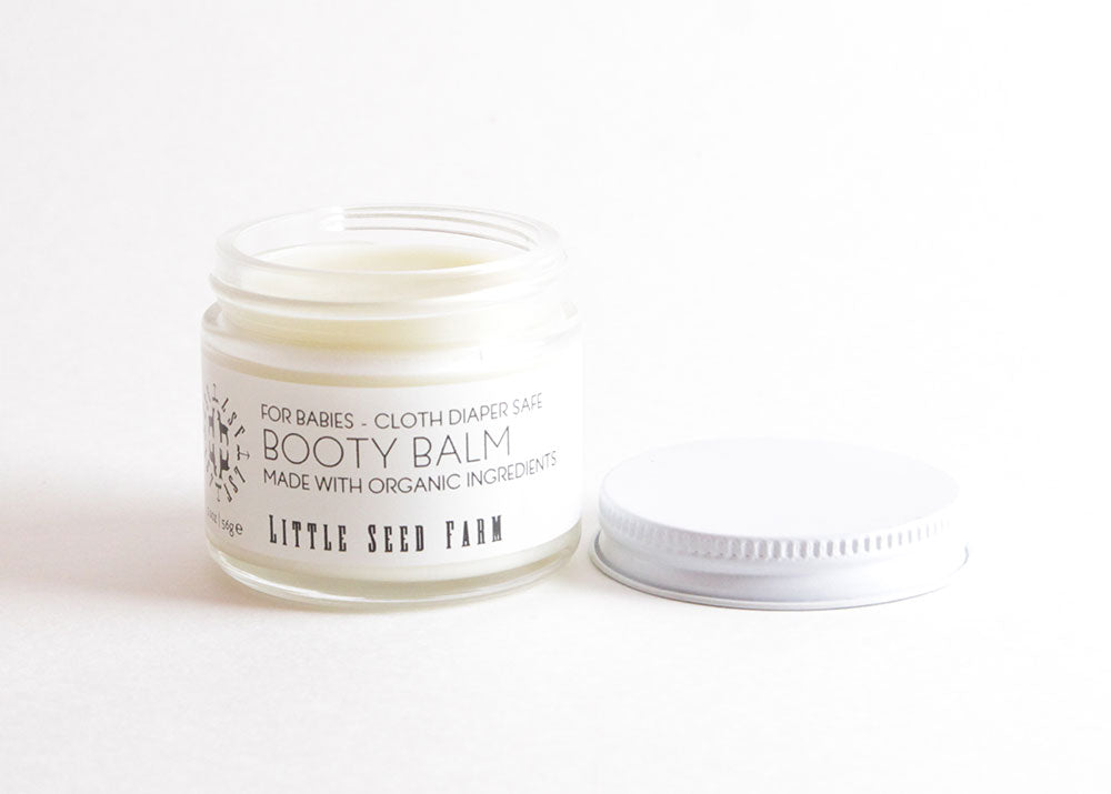 Little Seed Farm Baby Diaper Balm in a glass jar, a gentle yet potent salve made with herbally infused coconut oil, shea butter, and organic healing botanicals to soothe and protect delicate baby skin.