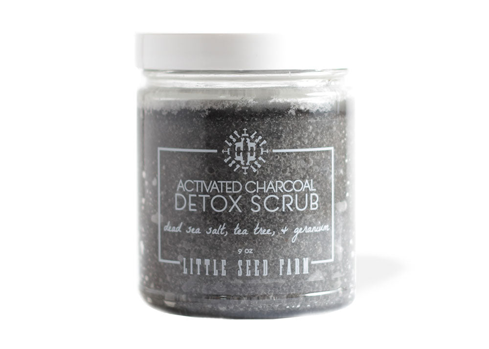 Activated Charcoal Detox Scrub in a refillable glass jar , featuring a deep-black exfoliant made with Dead Sea salt, activated charcoal, and organic coconut oil to detoxify and moisturize.