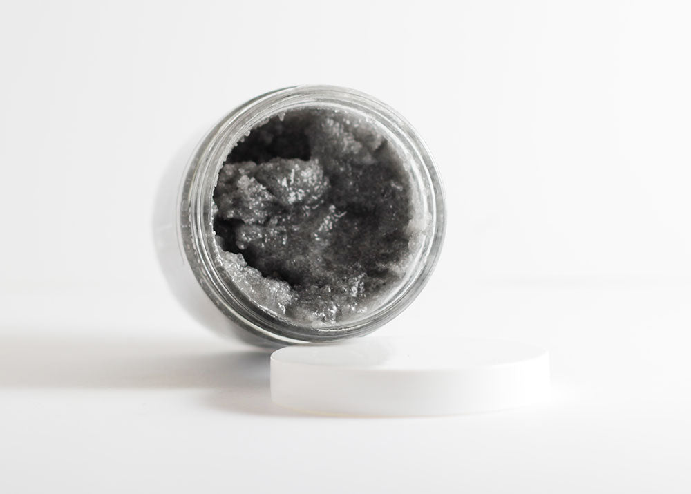 Close-up of the gritty, mineral-rich texture of the Activated Charcoal Detox Scrub highlighting its detoxifying Dead Sea salt and activated charcoal blend combined with nourishing oils for skin exfoliation and hydration.