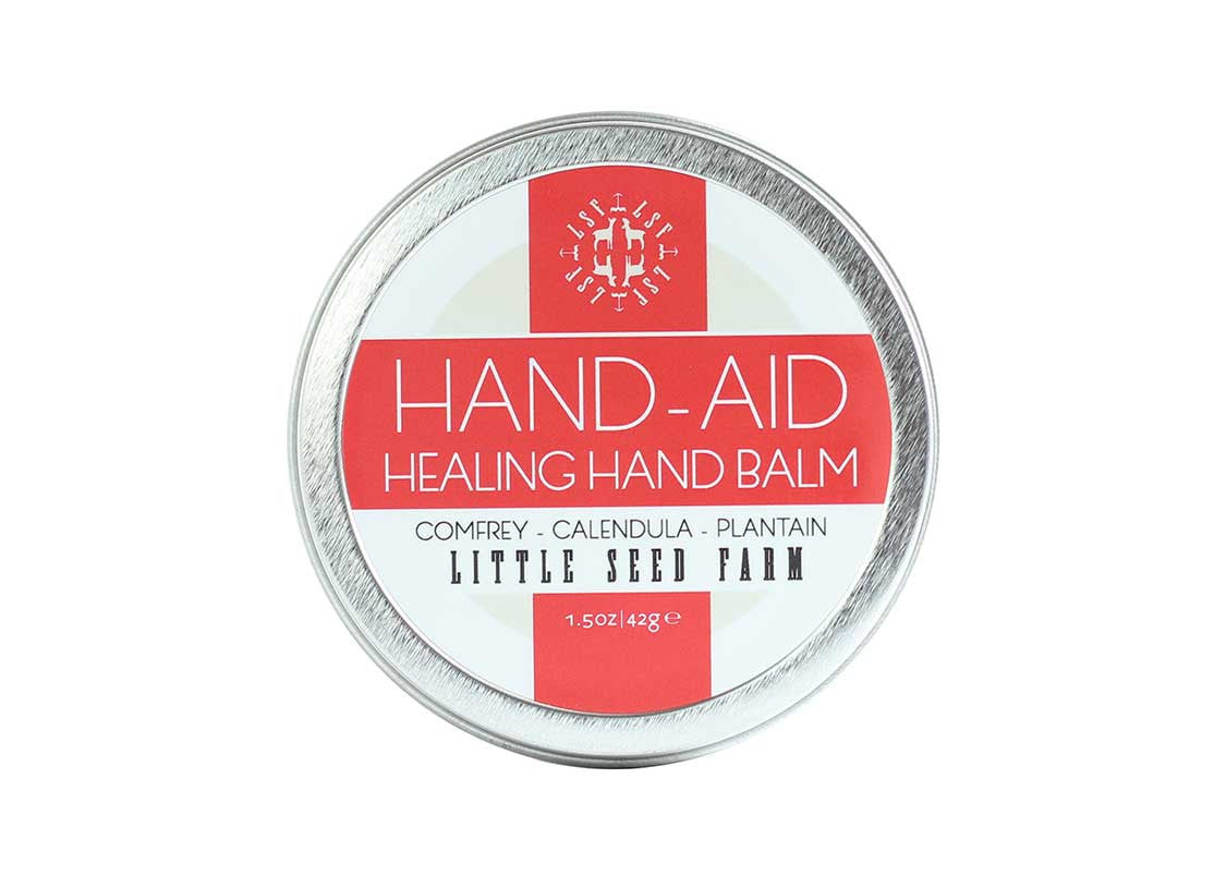 Closed tin of Original Hand‑Aid Healing Hand Balm showcasing minimalist packaging of an organic salve designed to heal, protect, and hydrate at‑risk skin”—formulated with plant-powered botanicals like comfrey, calendula, and plantain