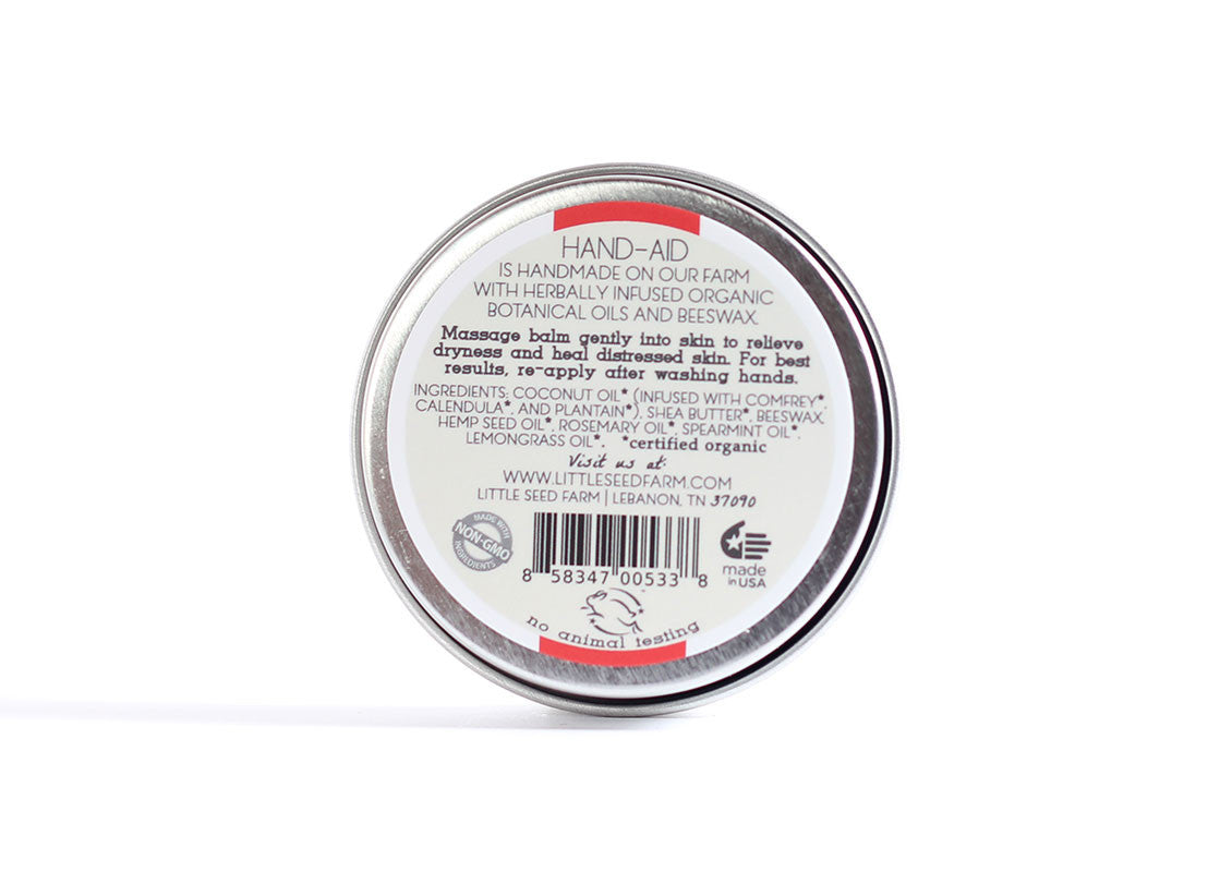 Back label of Little Seed Farm Original Hand‑Aid Healing Hand Balm listing certified organic ingredients—coconut oil infused with comfrey, calendula, and plantain; shea butter; beeswax; hemp seed oil; plus essential oils of rosemary, spearmint, and lemongrass.