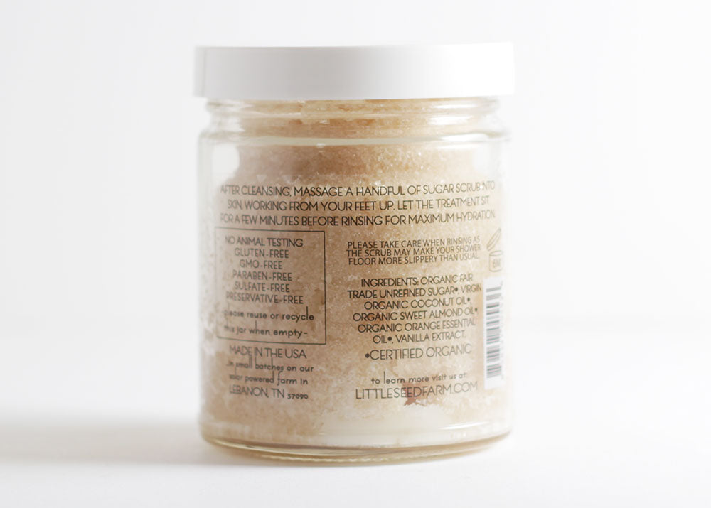 Back label of Organic Sugar Scrub listing certified organic ingredients: fair-trade raw sugar crystals, coconut oil, sweet almond oil, orange peel essential oil, vanilla extract, and vitamin E from non-GMO sunflower seeds.