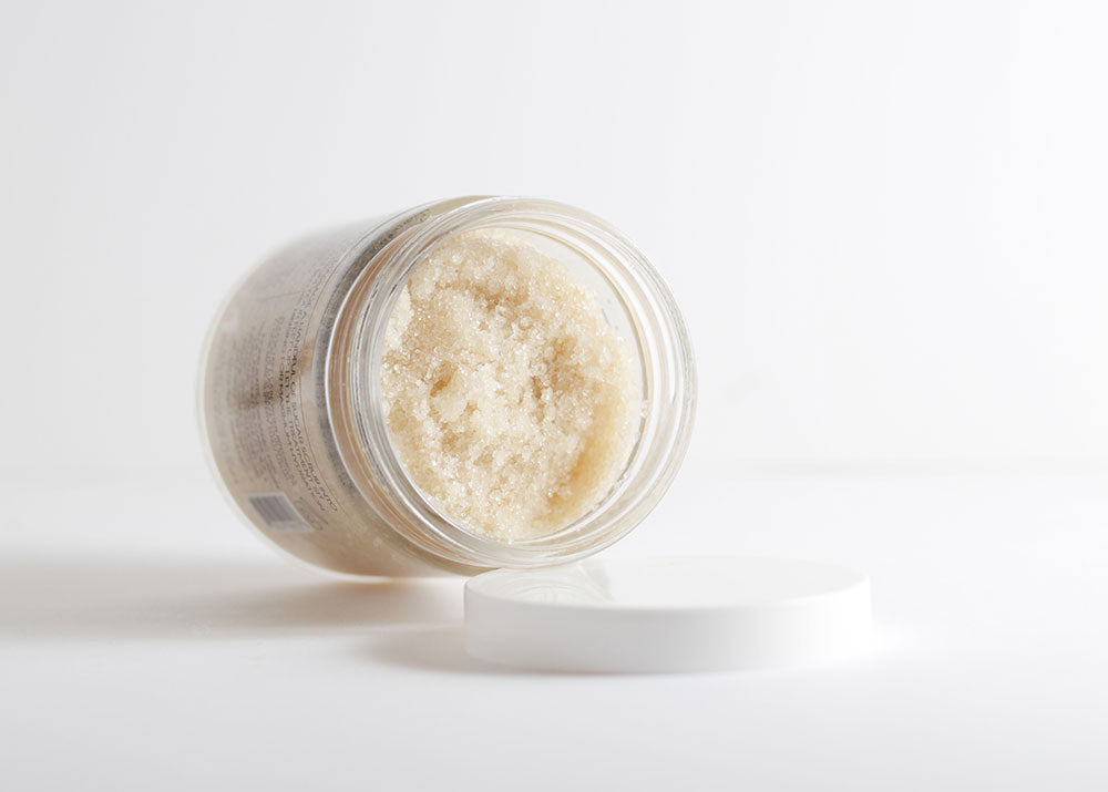 Rich, sugary scrub texture in a glass jar showing organic coconut and almond oils that nourish and leave skin ultra-soft while creating a hydrating lipid barrier.